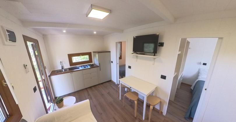 Gemütliches modernes Zuhause, kompakte Küche, Tisch, TV und helles Schlafzimmer.